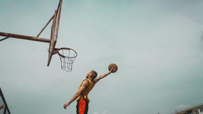 NBA篮球赛事直播预告图，室内篮球馆球员跳球瞬间，观众席座无虚席，灯光璀璨